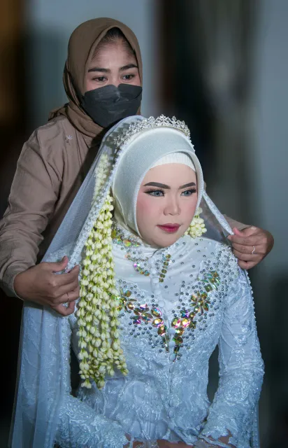 MUA merapikan hijab dan aksesori pengantin